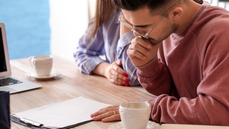 Zwei Personen sitzen an einem Tisch und lesen gemeinsam Dokumente