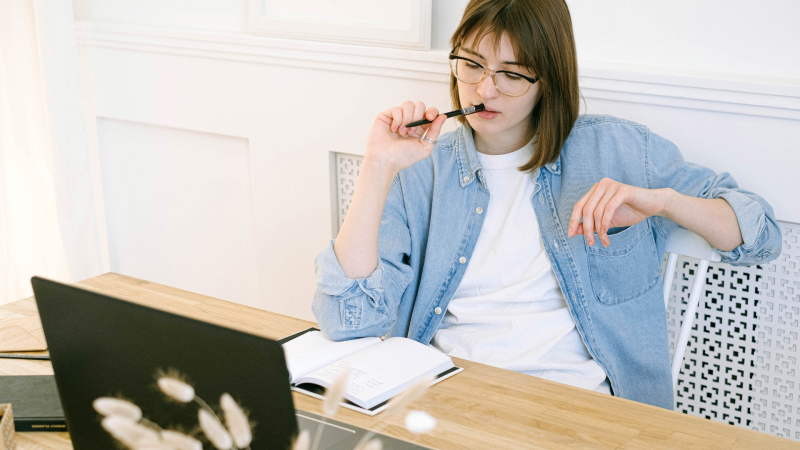 Freelancing 2026: Was sich ändert Eine Frau sitzt mit Brille und Stift am Laptop und arbeitet konzentriert im Home Office