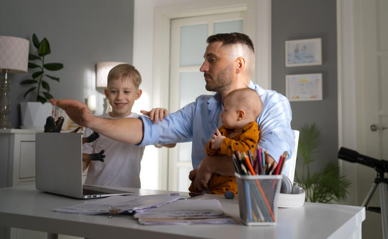 Vater arbeitet im Homeoffice mit zwei Kindern